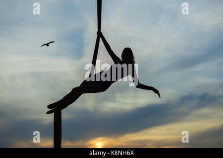 Frau Antenne Acrobat auf dem Hintergrund der untergehenden Sonne, macht sie die Tricks. Stockfoto