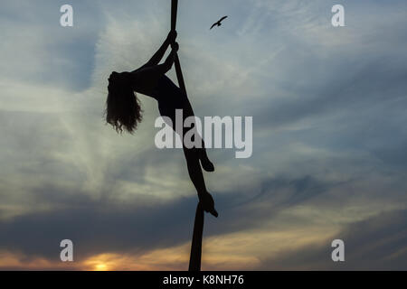 Frau Antenne acrobat Tänze in der Luft gegen den Himmel, zeigt sie die Tricks. Stockfoto