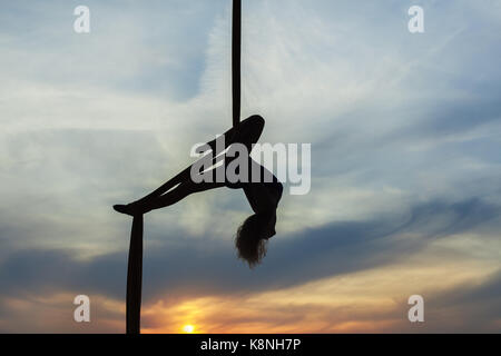 Woman's equilibrist hat Tricks hoch in den Himmel in die untergehende Sonne. Nur die Konturen der Athleten. Stockfoto