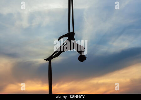 Frau in einer Hängematte die Tricks gegen den Himmel, sie ist ein Athlet Antenne Acrobat. Stockfoto