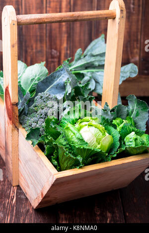 Vielzahl von Kohl in Holz- korb auf braunen Hintergrund. Ernte. Nahaufnahme Stockfoto