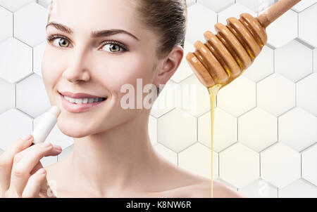 Junge Frau, lipbalm mit Honig auf die Lippen. Stockfoto