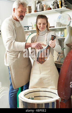 Tutor mit weiblichen Kursteilnehmer in der Töpferwerkstatt Feuern Vase in Ofen Stockfoto