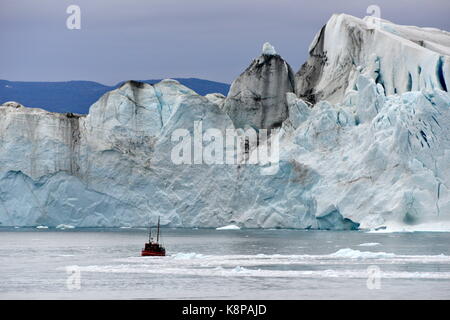 Ein Fischerboot mit Touristen an Bord macht seinen Weg zwischen Eisberge im Fjord in der Nähe von Ilulissat an der Westküste Grönlands. Die eisberge können 100 Meter über dem Wasserspiegel zu erreichen und sind rund 65 Kilometer entfernt auf der Kangia Gletscher gebildet. Dieses ist, wie 40 Millionen Tonnen Eis in den Fjord, die von der UNESCO als Weltnaturerbe seit 2004 eingestuft wurde. Genommen 22.08.2017. Foto: Karlheinz Schindler/dpa-Zentralbild/ZB | Verwendung weltweit Stockfoto