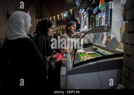 Erbil, Irak. 20 Sep, 2017. Eine kurdische Familie kauft Eis auf einem Markt mit der kurdischen Flagge in Erbil, Irak, 20. September 2017 eingerichtet. Erbil ist eine der Städte, die in einem umstrittenen Unabhängigkeit Abstimmung teilnehmenden am 25. September. Einen unabhängigen kurdischen Staat ist stark von der Zentralregierung in Bagdad und der westlichen Großmächte wie die USA. Credit: Oliver Weiken/dpa/Alamy leben Nachrichten Stockfoto