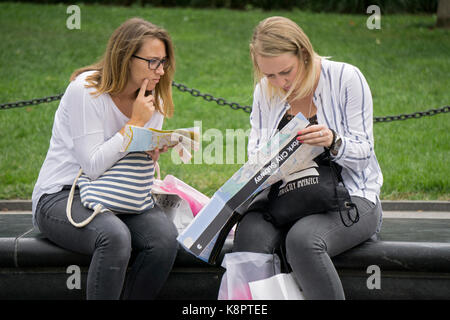 2 mystifizierten Frauen Touristen die Kontrolle einer Karte der New Yorker U-Bahn auf einer Bank in Washington Square Park in Greenwich Village, New York City. Stockfoto