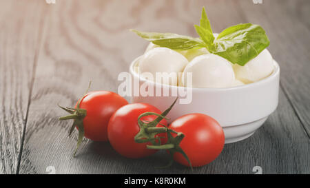 Kleine Mozzarellakugeln in weiße Schüssel mit Eiertomaten Stockfoto