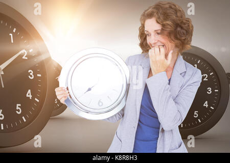 Besorgt Geschäftsfrau auf die Uhr gegen Digitales Bild von Uhren Suchen Stockfoto