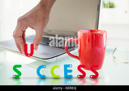 Zugeschnittenes Bild des Geschäftsmannes Anordnung erfolg Wort gegen Laptop auf dem Schreibtisch mit roten Becher und Gläser Stockfoto