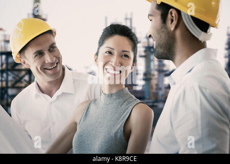 Happy Architekten diskutieren über Blueprint gegen Bild der Fabrik Stockfoto