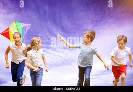 Die volle Länge der Boy holding Kite mit Freunden gegen die Ansicht der bewölkten Himmel Stockfoto