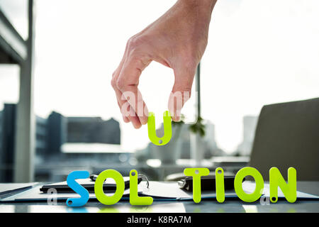 Zugeschnittenes Bild des Geschäftsmannes arrangieren Lösung Wort gegen Dokumente stellen auf dem Schreibtisch Stockfoto