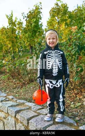 Trick oder Festlichkeit. glückliches Kind tragen Skelett Kostüm für Halloween im Freien holding Kürbis Jack O'Lantern Warenkorb Stockfoto