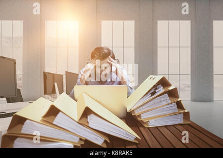 Frustriert Geschäftsmann mit Kopf in den Händen am Schreibtisch gegen Büromöbel sitzen Stockfoto