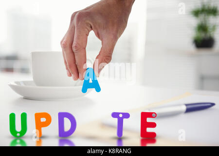 7/8-Seite arrangieren Wort gegen eine Tasse Kaffee, die auf dem Tisch Posing ist aktualisieren Stockfoto