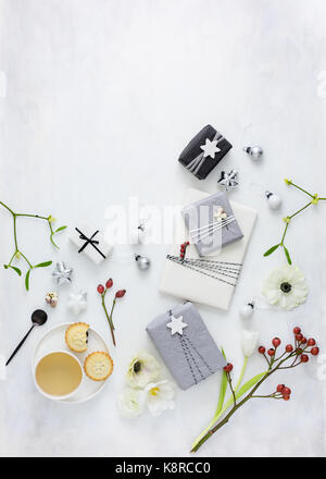 Verpackung Weihnachtsgeschenke mit Seidenpapier und Garn und Dekorieren mit Beeren und Sterne, trinken Kaffee und essen Kuchen. Stockfoto