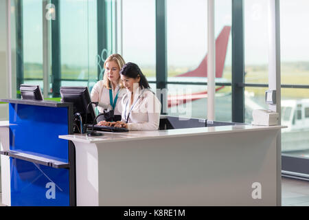 Das Bodenpersonal mit Computer am Schalter im Flughafen Stockfoto