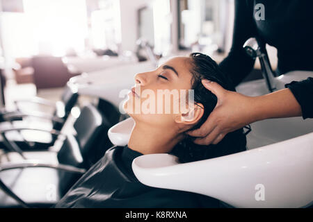 Weibliche friseur Spülung Haar von einem Kunden. Frau erhalten Haar Kur, die im Salon. Stockfoto