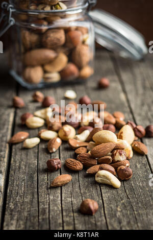 Verschiedene Arten von Nüssen. Haselnüsse, Walnüsse, Mandeln, Paranüsse, Pistazien auf alten Holztisch. Stockfoto