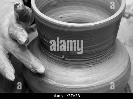 Prozess der Herstellung Geschirr auf der Töpferscheibe. Töpfer bei der Arbeit. Schwarz und weiß getönt. Stockfoto