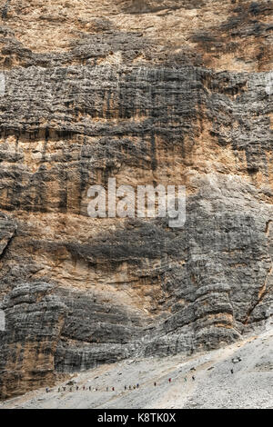 Die Dolomiten, Norditalien. Die winzigen Figuren der Wanderer unter der massiven Wand des Zimes de Fanes, auf der Alta Via 1 Long distance Path Stockfoto