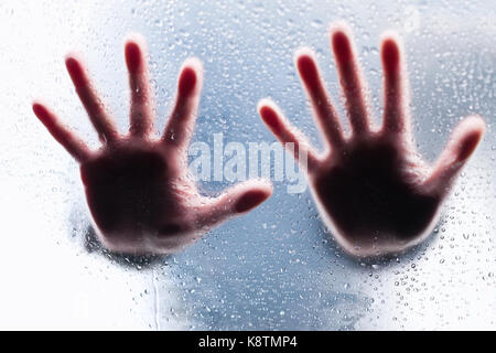 Silhouetten von zwei rechten Hände hinter nassen Glas Stockfoto