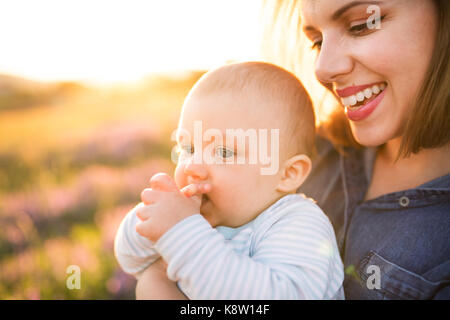 Junge Mutter in der Natur mit Baby Sohn in den Armen. Stockfoto