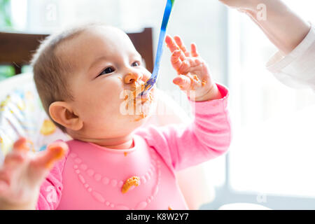 Mutter Fütterung Baby mit Löffel Stockfoto