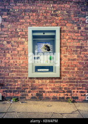 Ein VANDALIZED ATM GEGEN EINE Grunge Red Brick Wall Stockfoto