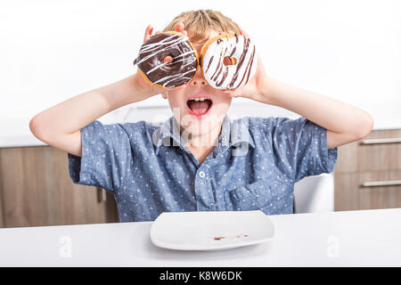 Kinder spielen mit Donuts in ihre Hände auf Ihr Gesicht Stockfoto