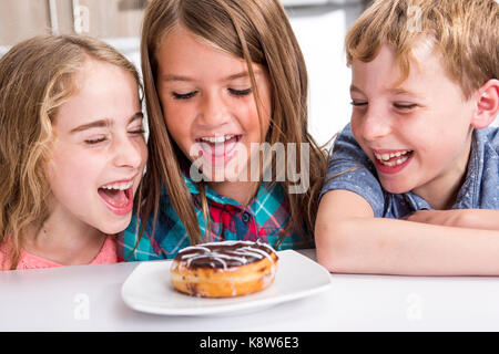 Junge Kind am Tisch sitzen Donut Stockfoto