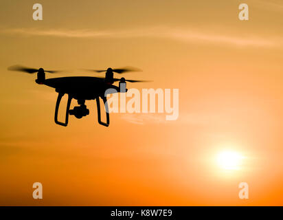 Quadrocoptern Silhouette vor dem Hintergrund der Sonnenuntergang. Fliegende Drohnen in den Abendhimmel. Stockfoto