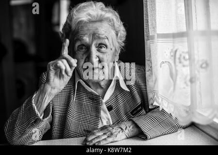 Ältere Frauen gestikuliert beim Sprechen, sitzen in der Nähe der Fenster. Schwarz-weiß Portrait. Stockfoto
