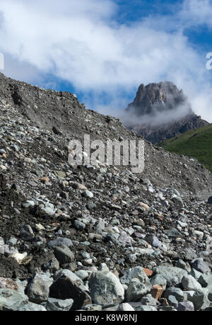 Steine aller Größen Wurf die Neigung von einem Gletscher Moräne mit einem Alaskan Berggipfel in der Ferne. Stockfoto