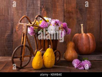 Herbst noch Leben - Kürbisse und Chrysanthemen Strauß vor dem Hintergrund der alten hölzernen Wand. Stockfoto