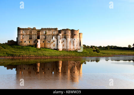 Ein Blick auf Carew Castle, Pembrokeshire, Wales, UK. Am Abend im goldenen Sonnenlicht mit das Schloss im Carew Einlass bei Ebbe wider genommen Stockfoto