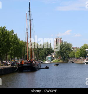 Traditionelle Segelschiffe entlang Westersingel Kanal im Zentrum von Leeuwarden, Friesland, Niederlande vertäut. Im Hintergrund iconic Oldehove Tower. Stockfoto