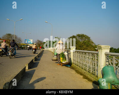 Hue, Vietnam - 13. September 2017: Nicht identifizierte Frau die Brücke überqueren und in die Schultern das Essen in der Stadt Hue, Vietnam Stockfoto