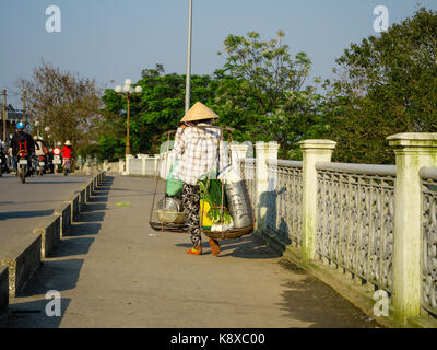 Hue, Vietnam - 13. September 2017: Nicht identifizierte Frau die Brücke überqueren und in die Schultern das Essen in der Stadt Hue, Vietnam Stockfoto