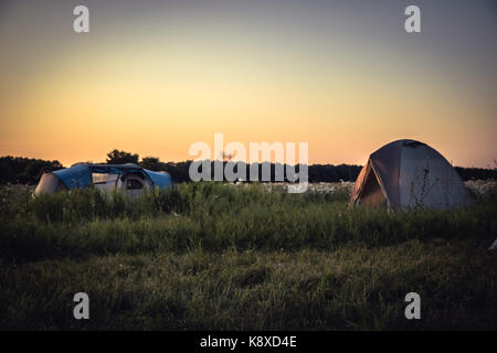 Campingplatz camping Zelten auf Hintergrund auf Sommer ländlichen Bereich und orange Sonnenuntergang Himmel beim camping urlaub Stockfoto