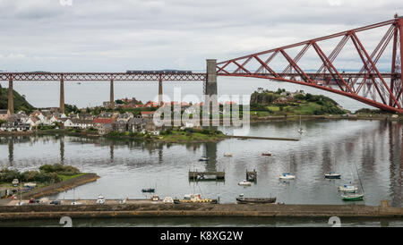 Beförderung Zwei lokale ScotRail Zug am Ausleger Forth Rail Bridge über den Firth-of-Forth, North Queensferry, Schottland, Großbritannien, mit Hafen im Vordergrund. Stockfoto