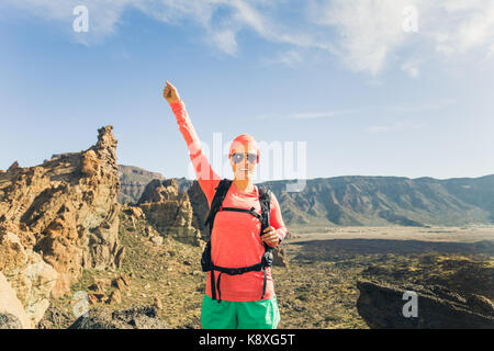 Frau Wanderer mit ausgestreckten Armen in den Bergen. Schönheit Läuferin, Hände hoch und inspirierende Landschaft auf Rocky Trail Wanderweg auf Teneriffa genießen. Stockfoto