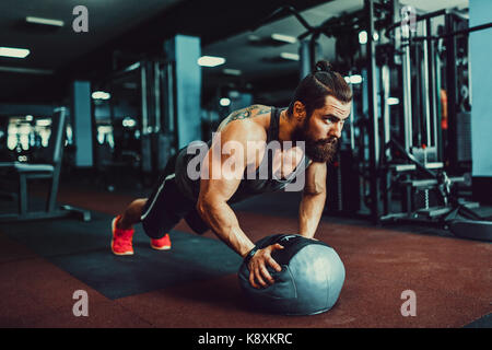 Es Planke! Zuversichtlich muskulösen jungen Mann mit Sport Verschleiß und tun Ganzkörperstütz während des Trainings auf dem Boden im Loft Innenraum Stockfoto