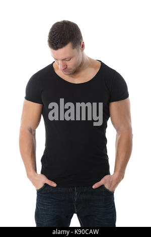 Stattliche Mitte erwachsener Mann im schwarzen T-Shirt stand mit den Händen in den Taschen vor weißem Hintergrund Stockfoto