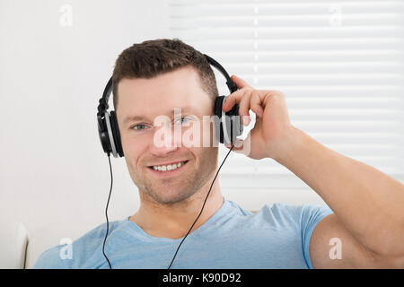 Portrait von lächelnden Mitte der erwachsene Mann Hören von Musik über Kopfhörer zu Hause Stockfoto