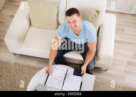 Hohe Betrachtungswinkel und der Mitte der erwachsene Mann Berechnung home Finanzen am Tisch Stockfoto