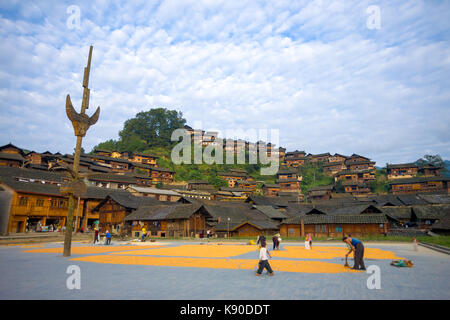 Xijiang, China - 15. September 2007: Dorfbewohner Trocknung Mais am Marktplatz unterhalb der wunderschöne Holz- hang Häuser in ethnischen Minderheit Miao villag Stockfoto