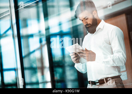 Hübscher junger Geschäftsmann über seine digitalen Tablet Stockfoto