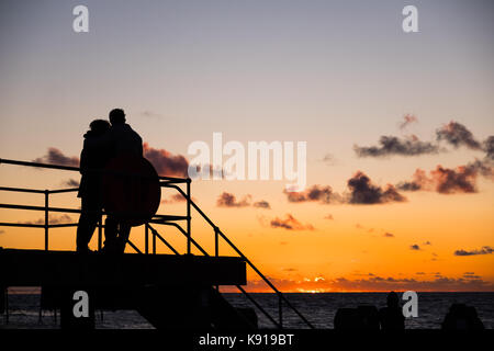 Aberystwyth Wales UK, Donnerstag, den 21. September 23017 UK Wetter: Am Vorabend der Herbst-tagundnachtgleiche, ein paar stehen zusammen wie die Sonne über dem Meer in Aberystwyth an der Küste von West Wales Photo Credit: Keith Morris/Alamy leben Nachrichten Stockfoto