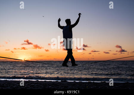 Aberystwyth Wales UK, Donnerstag, den 21. September 23017 UK Wetter: Am Vorabend der Herbst-tagundnachtgleiche, Jesse stecken, ein 3. Jahr Student Studium der Astrophysik an der Universität Aberystwyth, Praktiken seiner Slack-line Fähigkeiten, wie die Sonne über dem Meer setzt auf aberystwyth an der Küste von West Wales Photo Credit: Keith Morris/Alamy leben Nachrichten Stockfoto